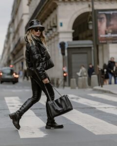 Fashionably dressed woman crossing a pedestrian lane in Paris, showcasing stylish urban fashion.